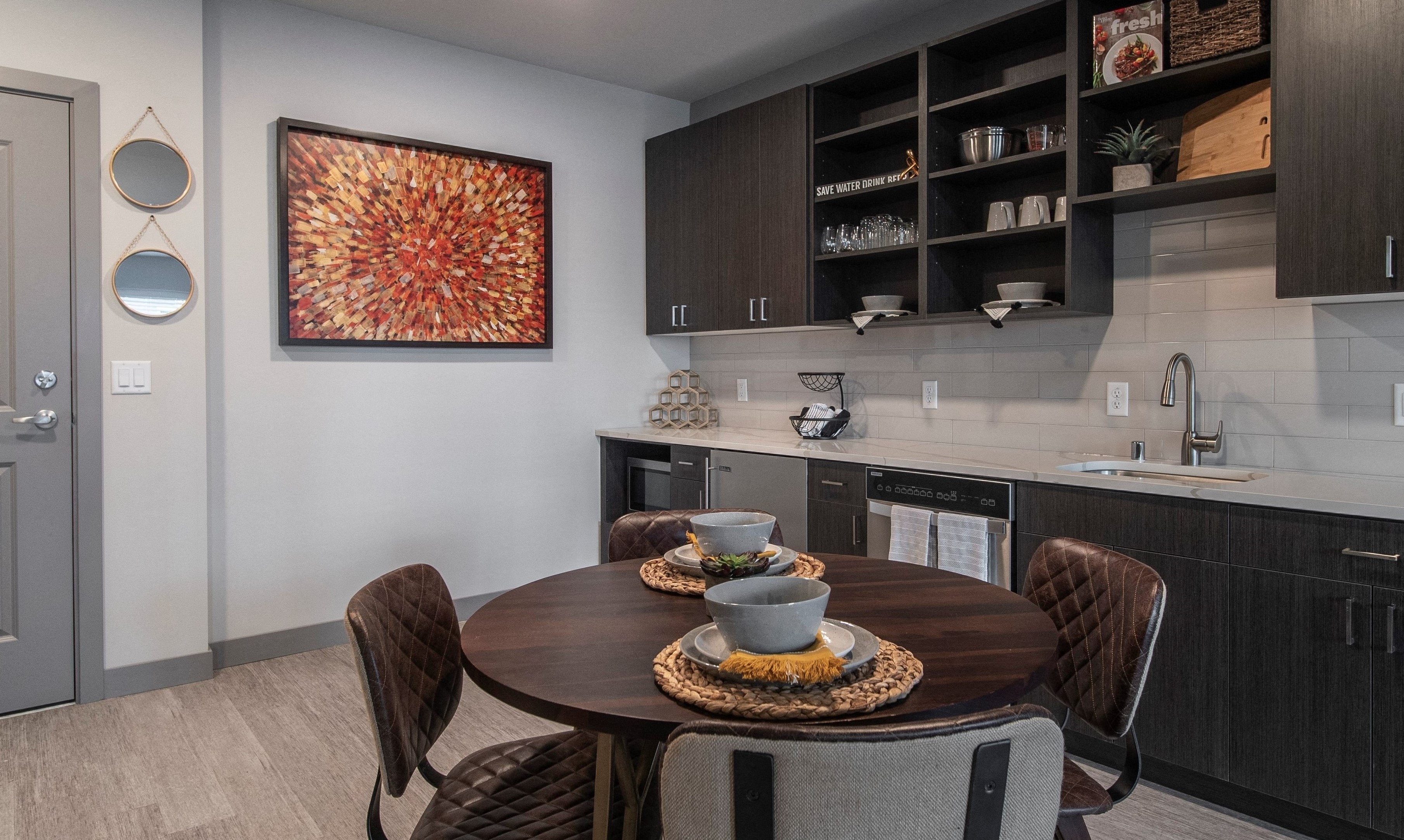 Kitchen area with dark wooden four-person dining table, cabinetry, and stainless steel appliances