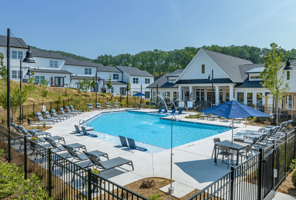 a swimming pool with chairs and umbrellas in front of a building