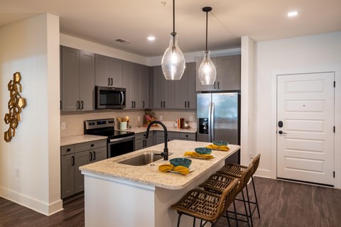 A kitchen with a white island and brown chairs.
