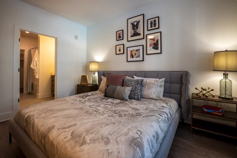 A bedroom with a large bed and a nightstand with a lamp.