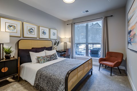 A bedroom with a bed, chair, and pictures on the wall.