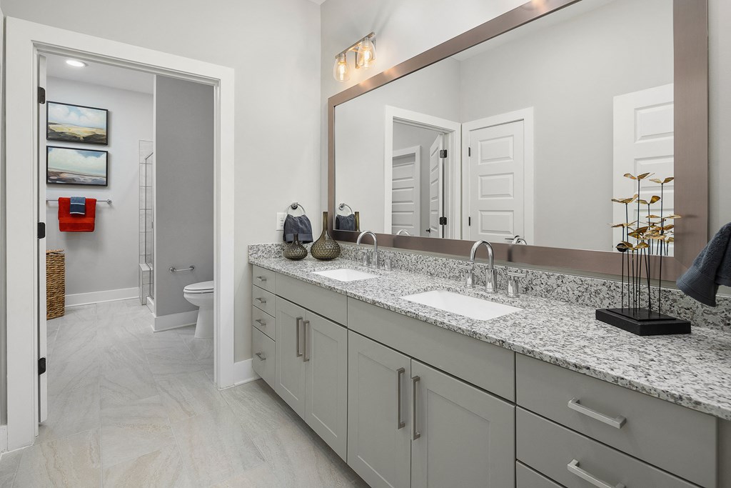 A bathroom with a white counter top and a large mirror.