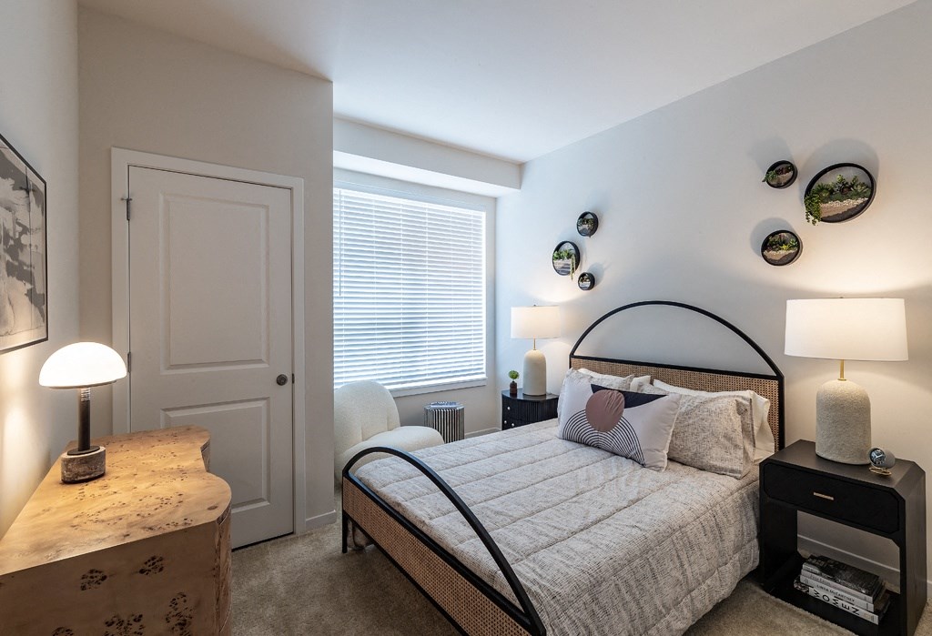 a bedroom with a bed and lamps and a window