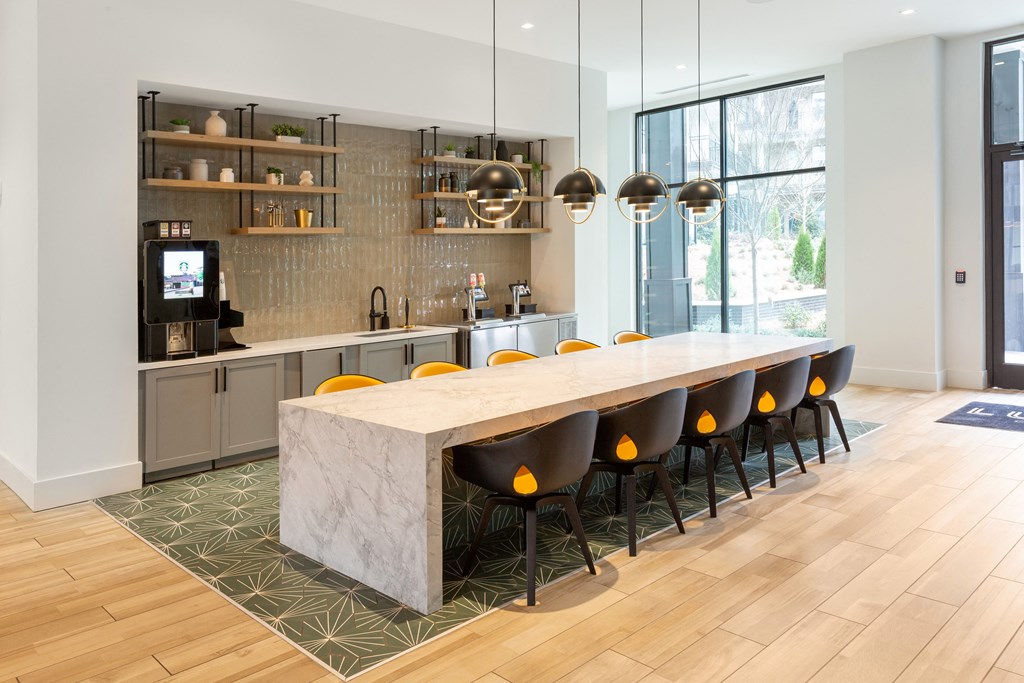 a kitchen with a marble counter top and a long table with yellow chairs