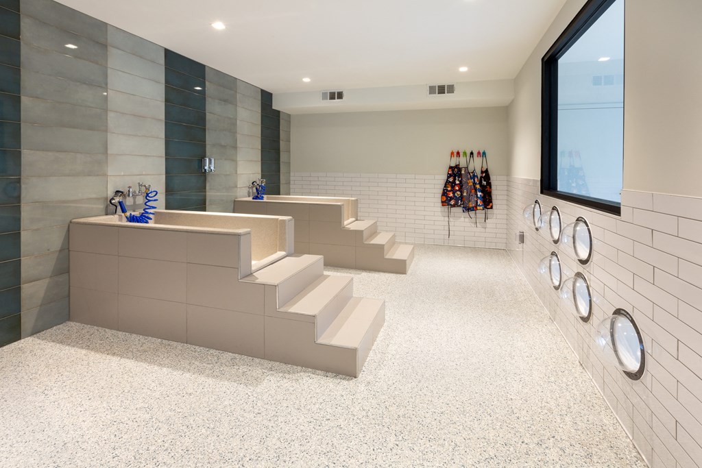 a set of stairs in a gym with white tile walls and a row of weights