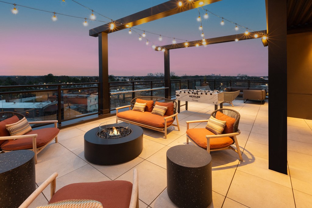 a rooftop terrace with chairs and tables and a fire pit