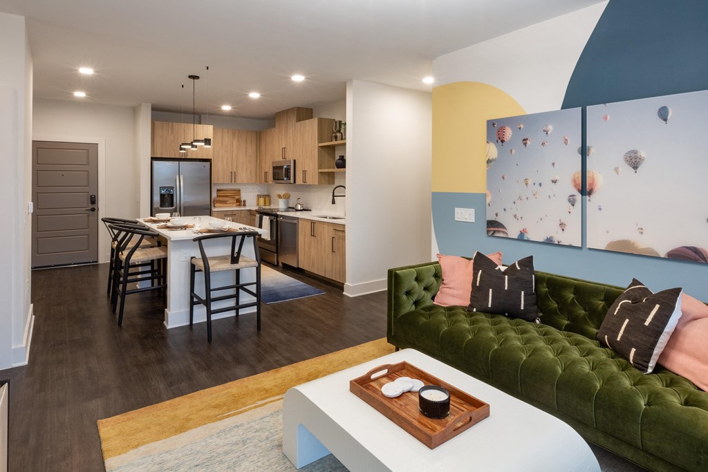 a living room and kitchen with a green couch and a table