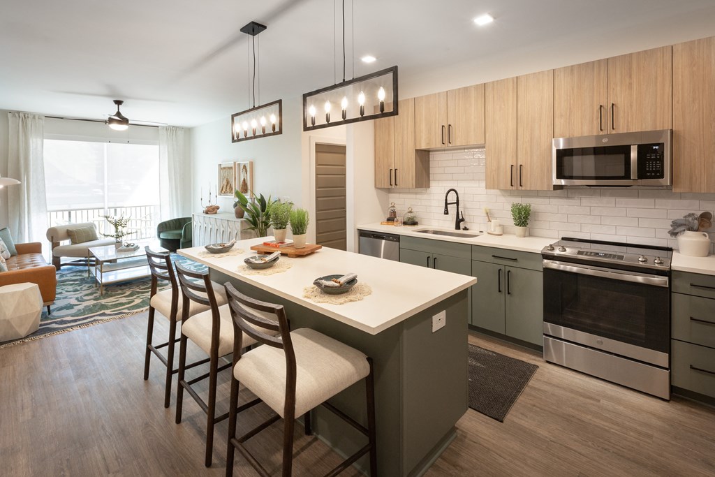 an open kitchen and living room with a large island with stools