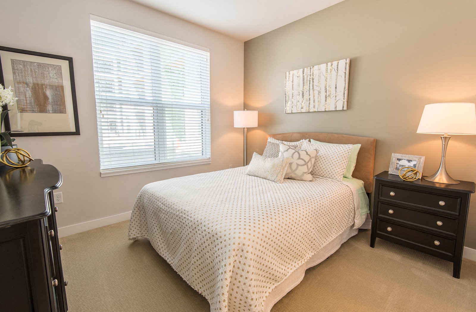 Carpeted bedroom with a bed near a large window, a dresser, and a nightstand. 