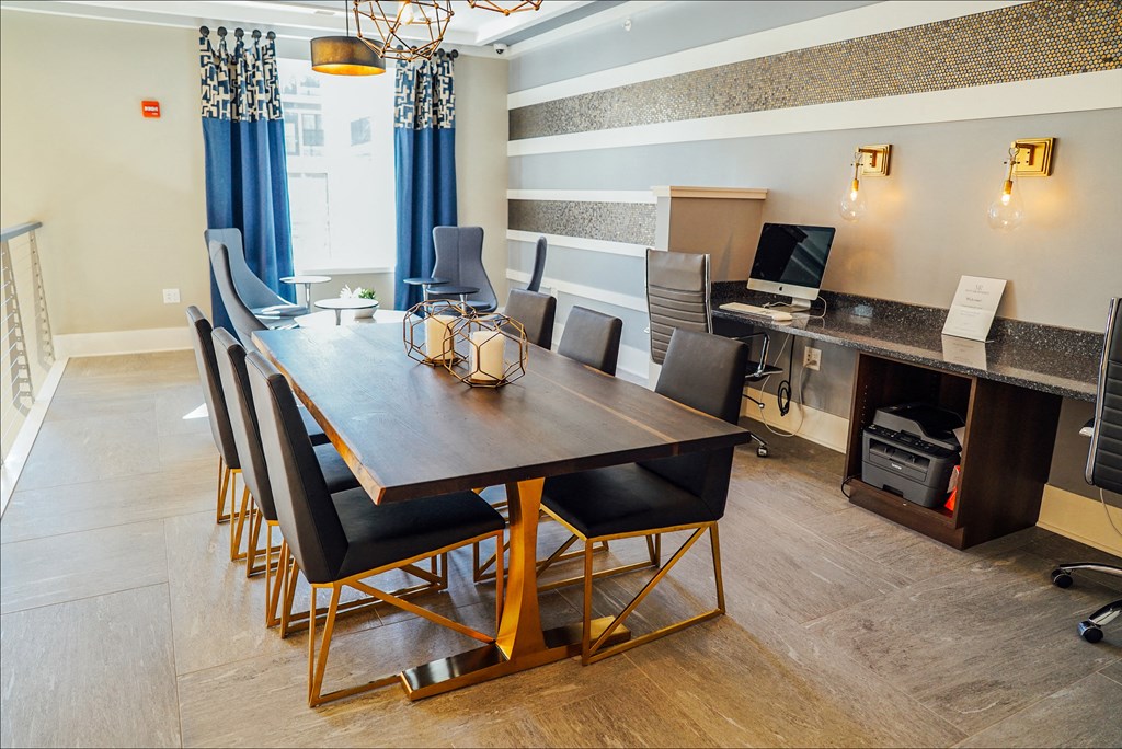 Business center with tables and seating, printer, and a desktop computer. 