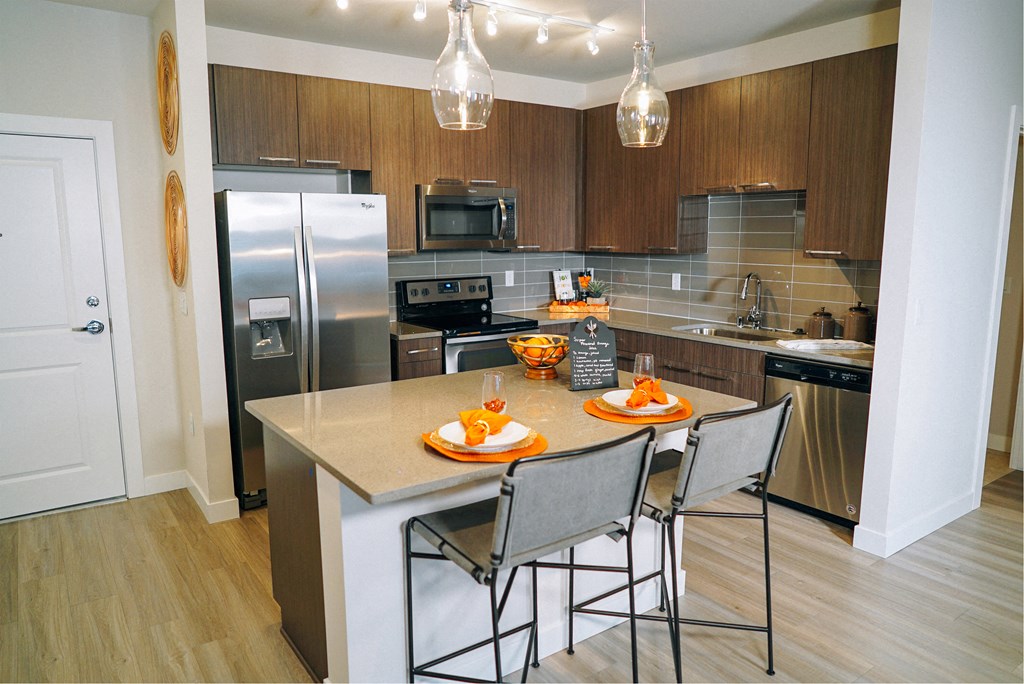 Kitchen area with a small kitchen island, dark wooden cabinets, and stainless steel appliances. 