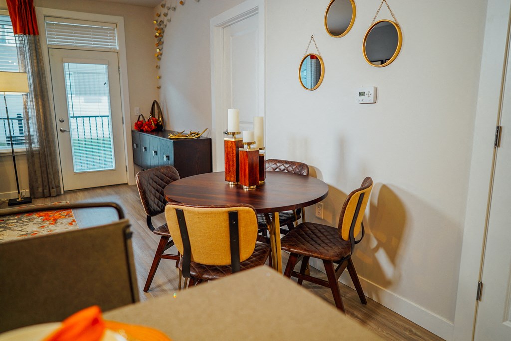 Circular dining room table with 4 chairs between the living room and kitchen area.