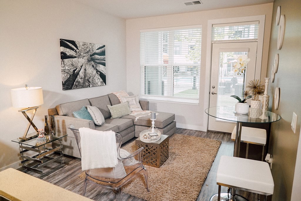 Furnished living room area with a large window and door with window in the middle facing the pool area. 
