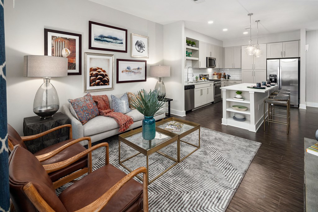 A modern living room with a white couch, a coffee table, and a kitchen in the background.