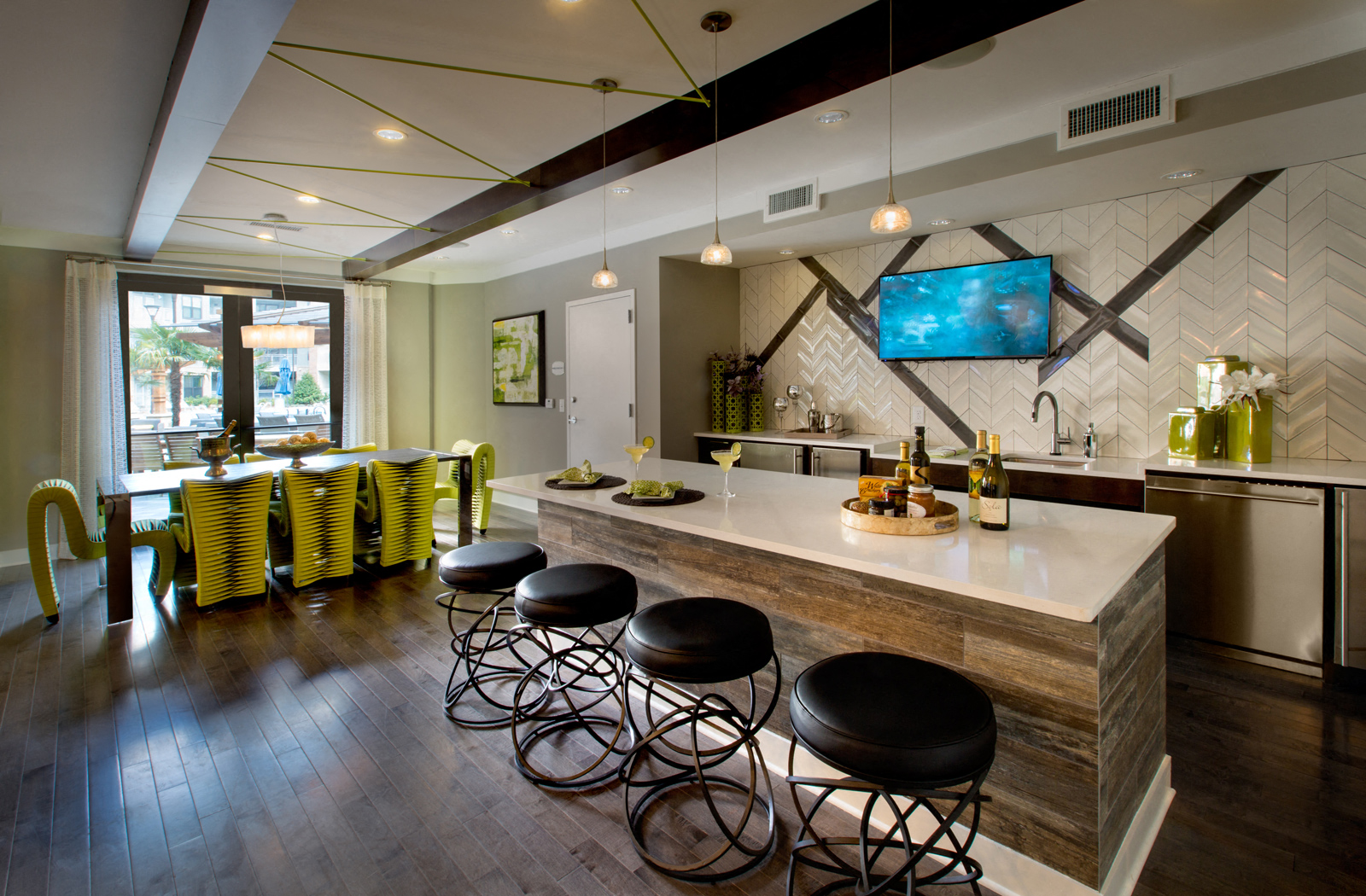 Community kitchen with kitchen island, mini fridge, long table, and a large window. 
