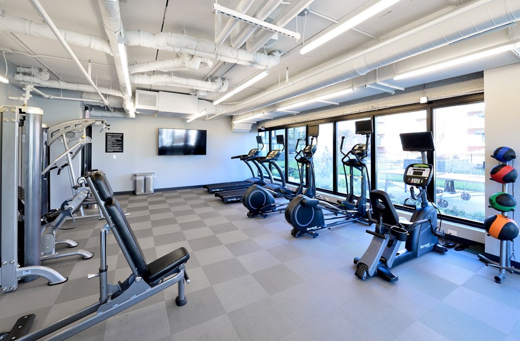 a gym with cardio equipment and a tv on the wall