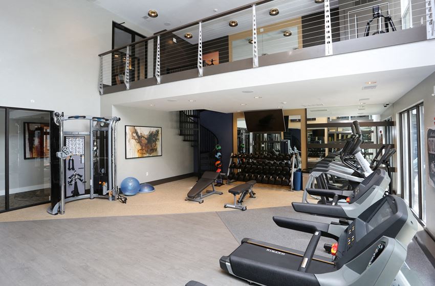 Two-leveled fitness center area with multiple work out equipment.
