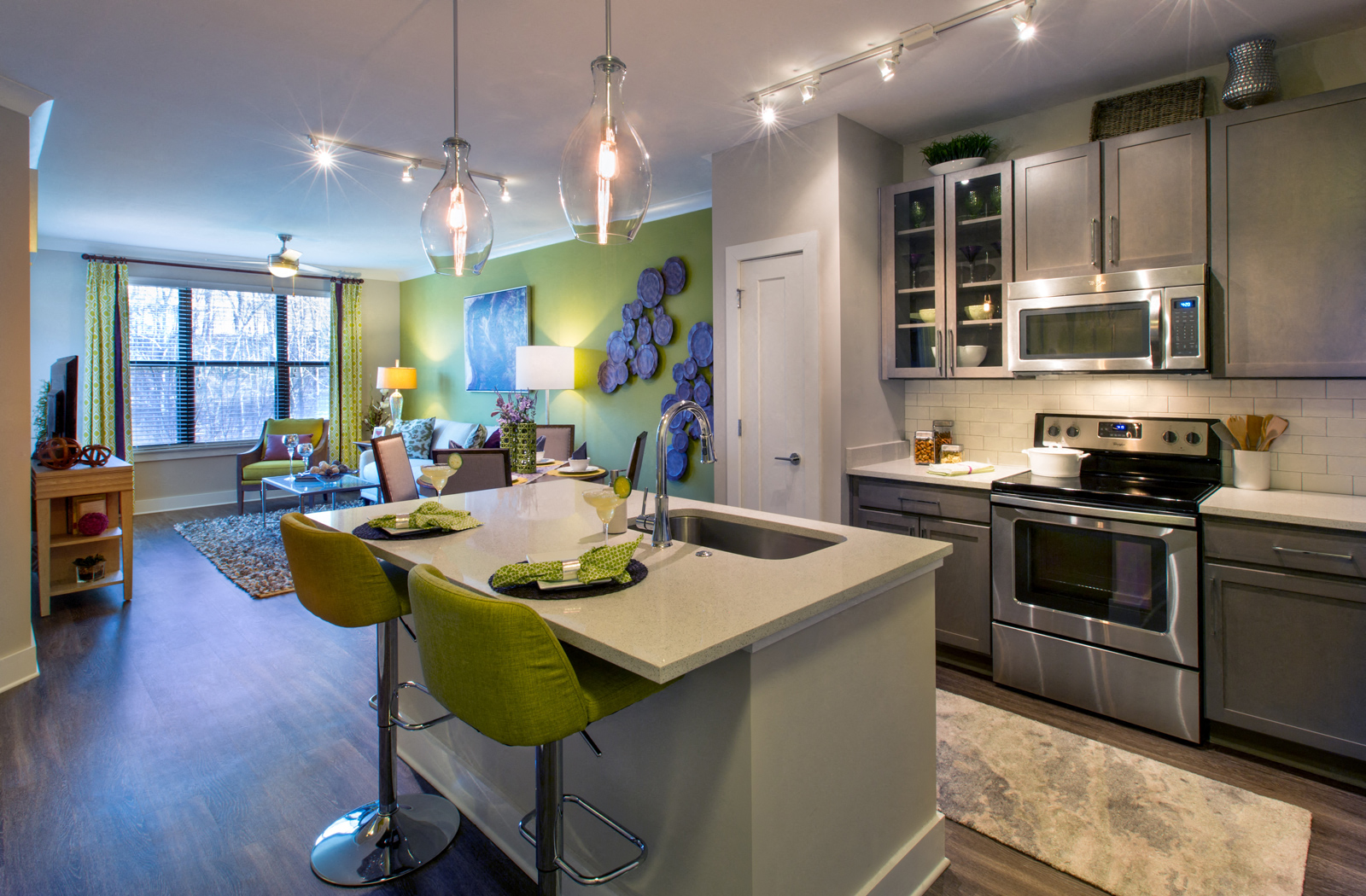 Kitchen area with a kitchen island and stainless steel appliances connected to the living room area.