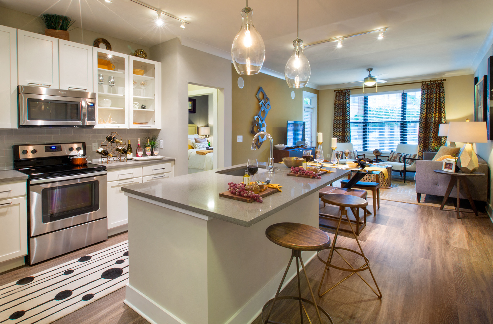 Kitchen area connected to the living room area with the door to the bedroom in the middle.