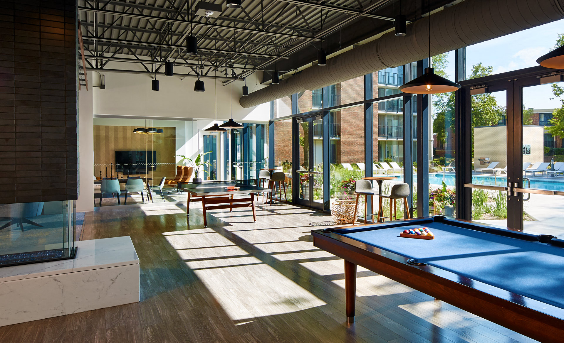Lounge area with pool table, table tennis, and large windows facing the pool area.