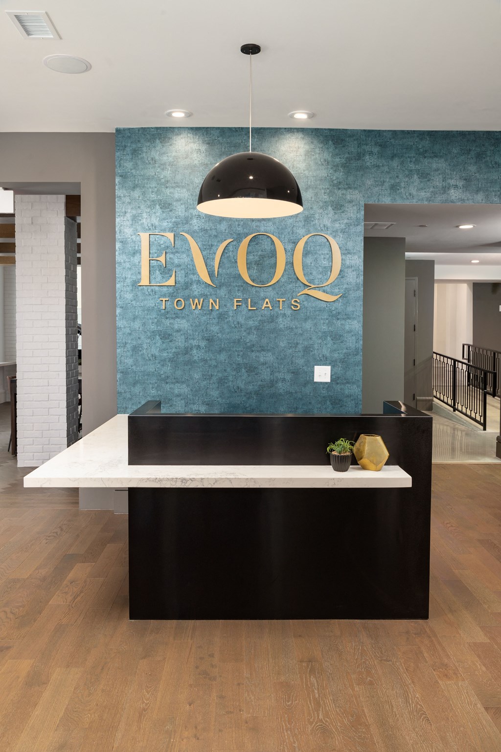 A reception desk with a white counter and a black base with a gold vase on it.
