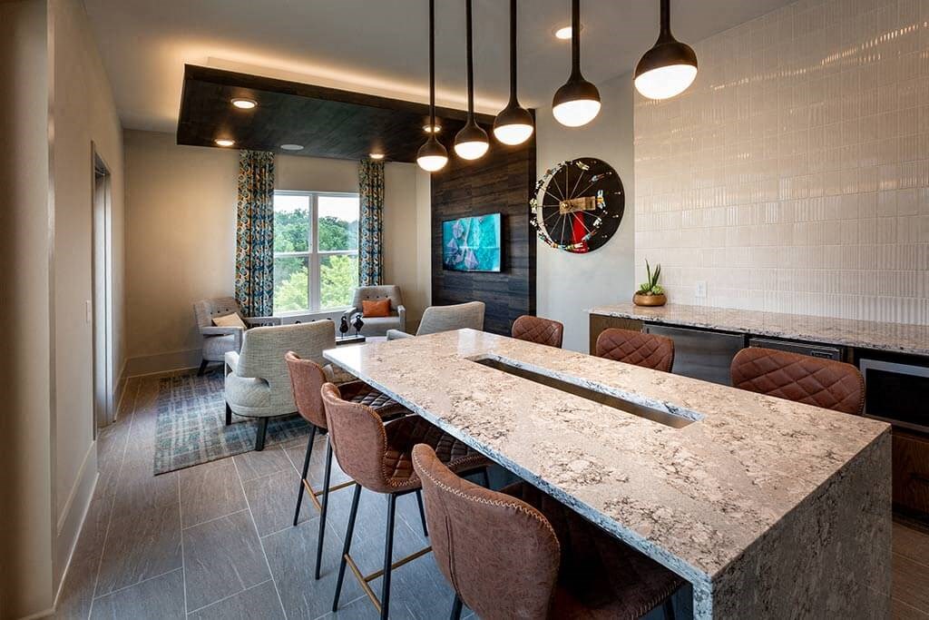 Resident lounge with a long table and 6 chairs, a big screen TV and additional seating.