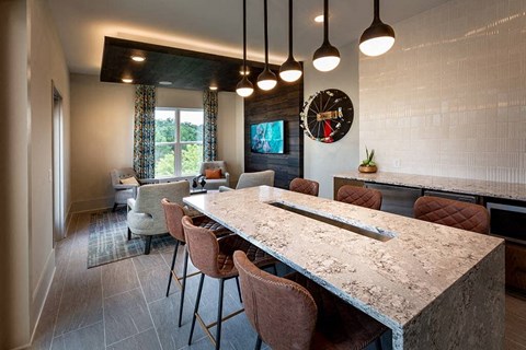 Resident lounge with a long table and 6 chairs, a big screen TV and additional seating.