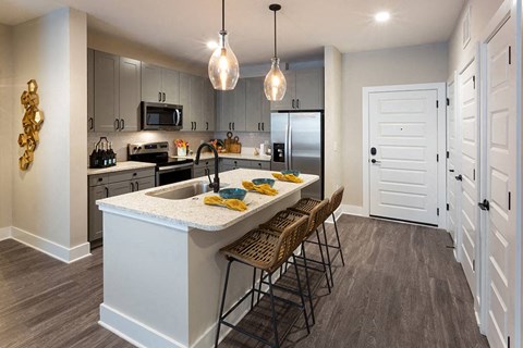 Kitchen with stainless steel appliances and a breakfast bar and 3 stools.