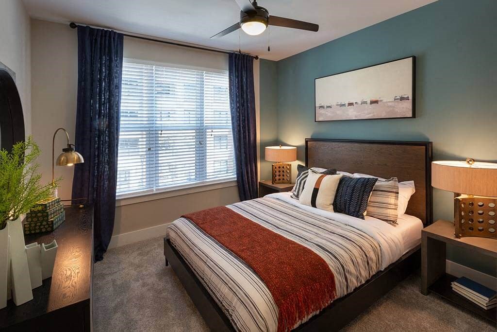 Bedroom with a queen sized bed and large window.