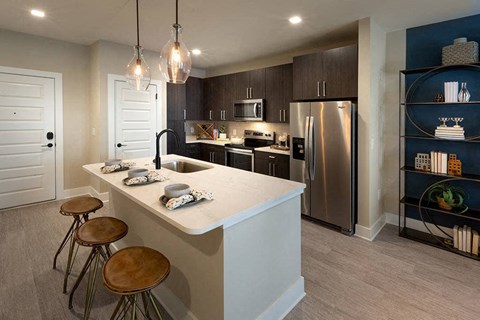A modern kitchen with a white island and stools.