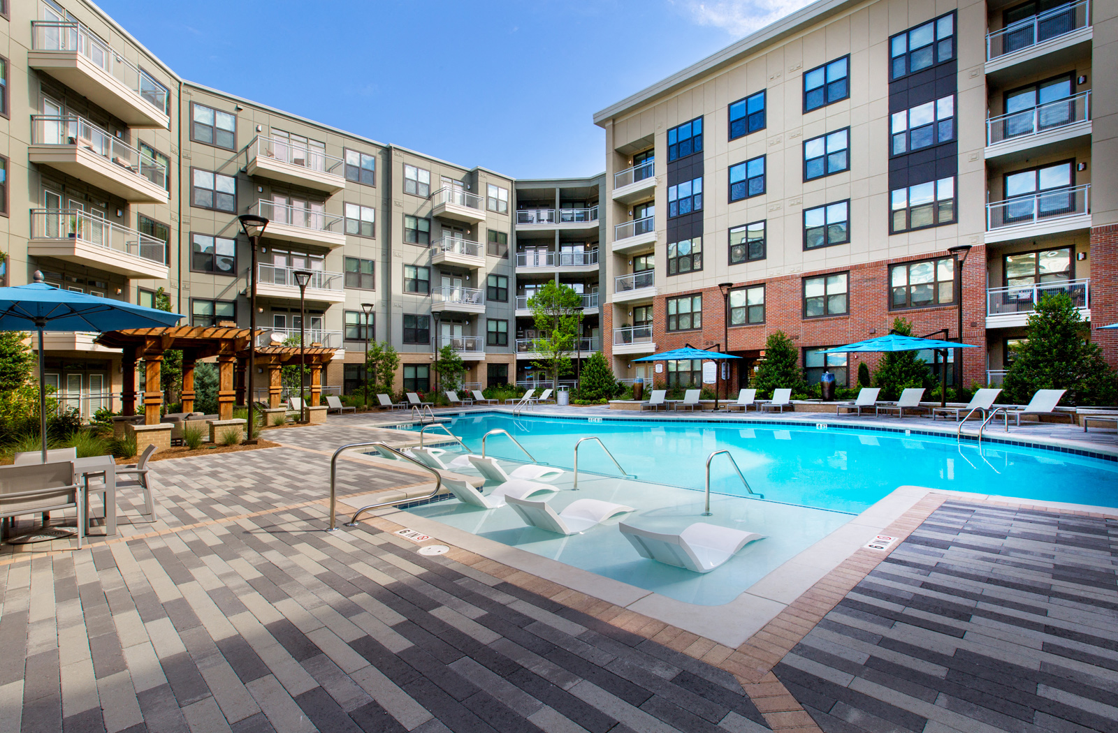 Outdoor pool area with multiple lounge chairs and shaded seating areas. 