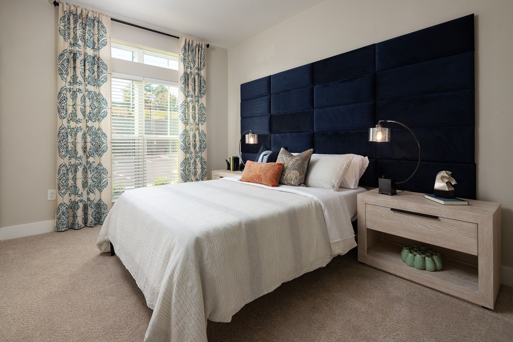 A bedroom with a large bed and a nightstand with a lamp.