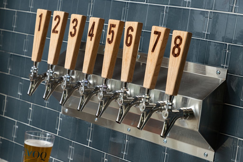 A beer tap with numbered handles is shown with a glass of beer in the foreground.