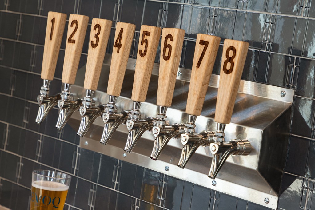 A beer tap with number 1 on it is next to a glass of beer.