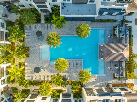 an aerial view of a resort with a swimming pool and palm trees