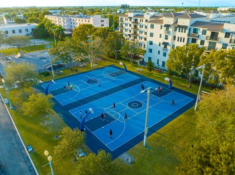 a group of people playing basketball on a blue court in a park