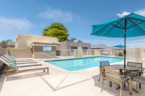 View of pool from sundeck with lounge chairs and picnic table in the foreground.