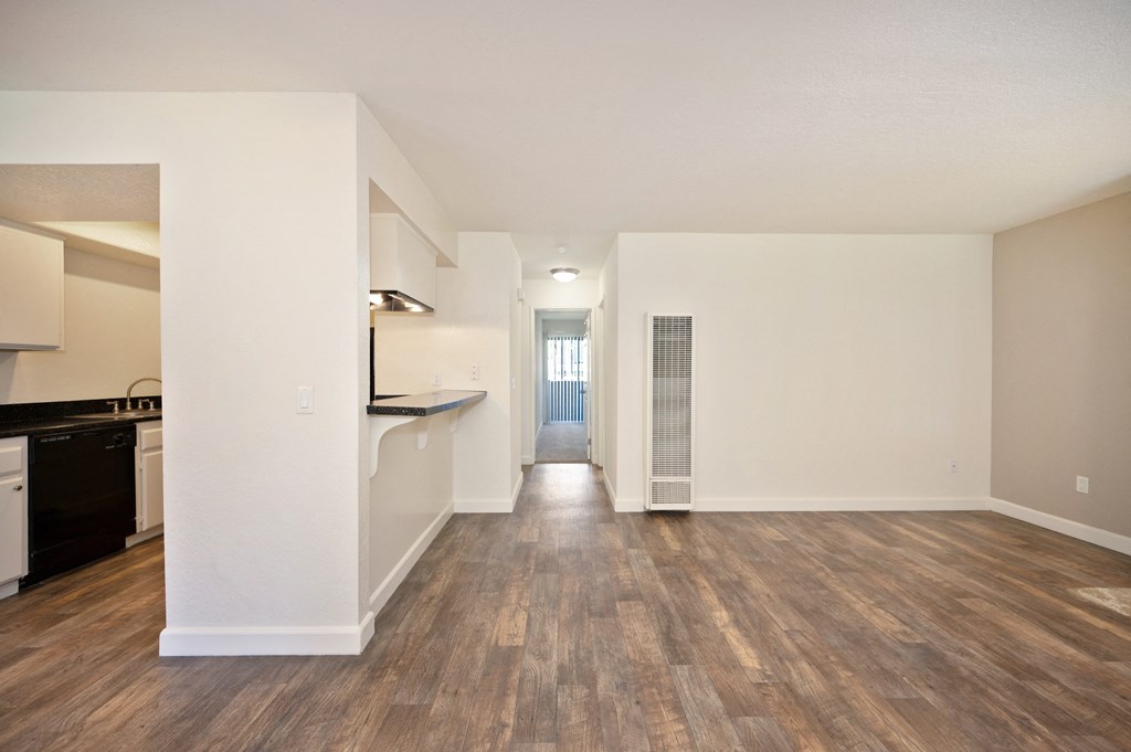 the living room and kitchen of an apartment with wood flooring