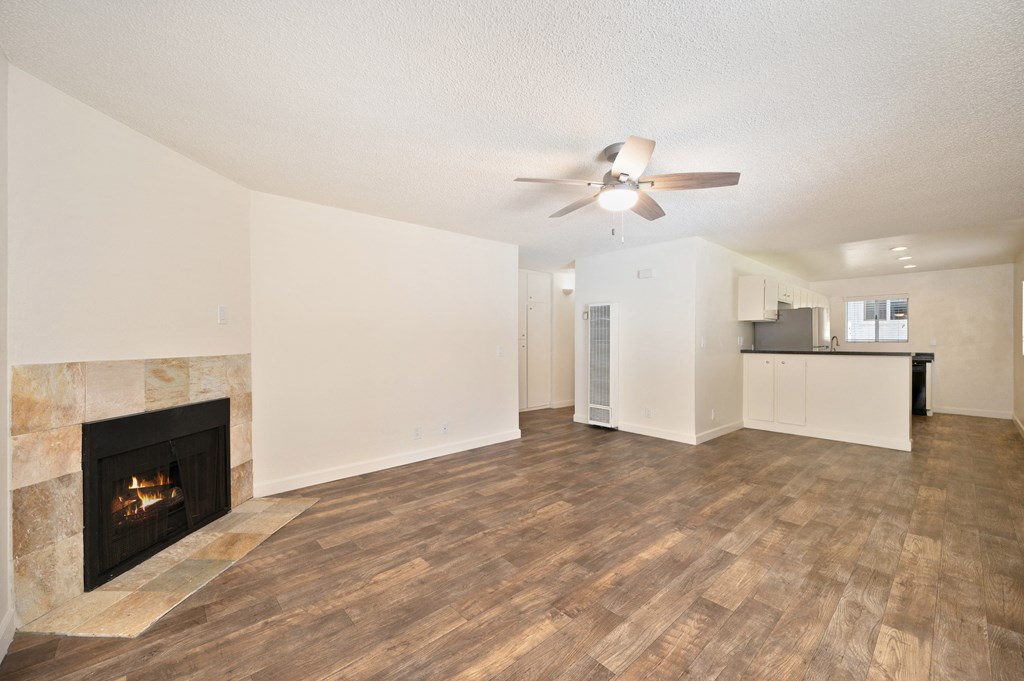an empty living room with a fireplace and a ceiling fan
