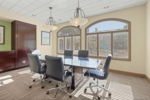 Conference room with overhead lights, table, office chairs, and large windows.