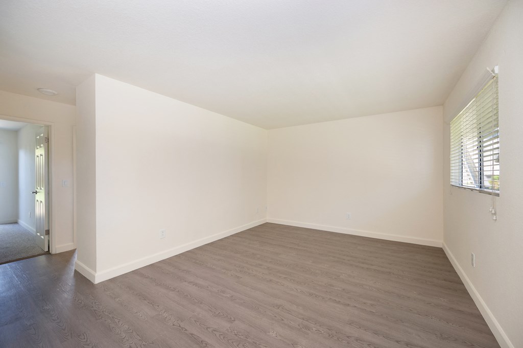 an empty living room with white walls and wood flooring