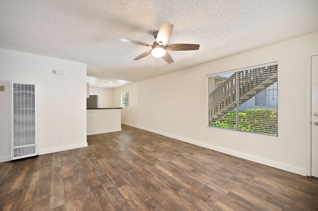 the living room and kitchen of an apartment with a ceiling fan