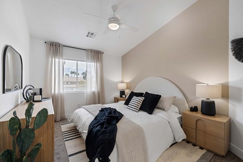 Carpeted bedroom with vaulted ceilings, ceiling fan, and window with horizontal blinds.