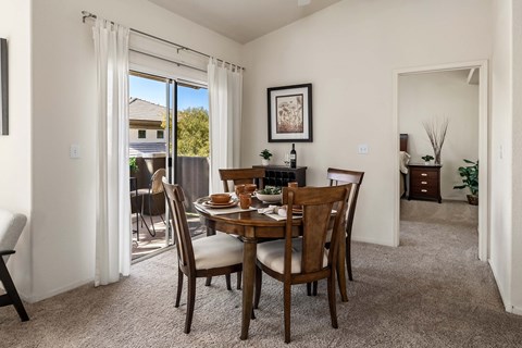 Carpeted dining room with view to balcony and bedroom.