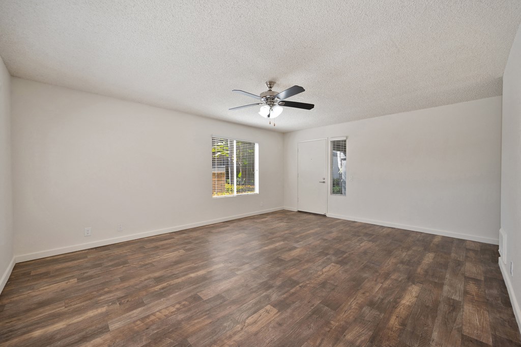 an empty living room with a ceiling fan and a window