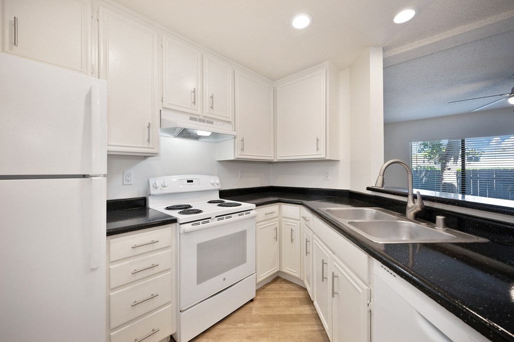 a kitchen with white appliances and black counter tops and white cabinets