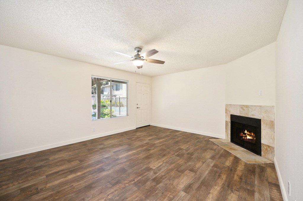 an empty living room with a fireplace and a ceiling fan