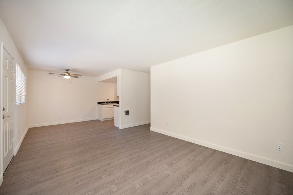 an empty living room with white walls and wood flooring