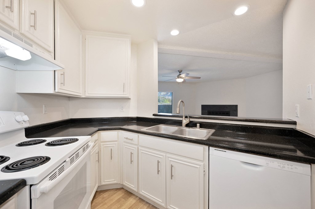 a kitchen with white appliances and black counter tops and white cabinets