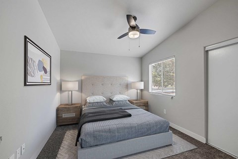 A bedroom with a bed, two lamps, and a ceiling fan.